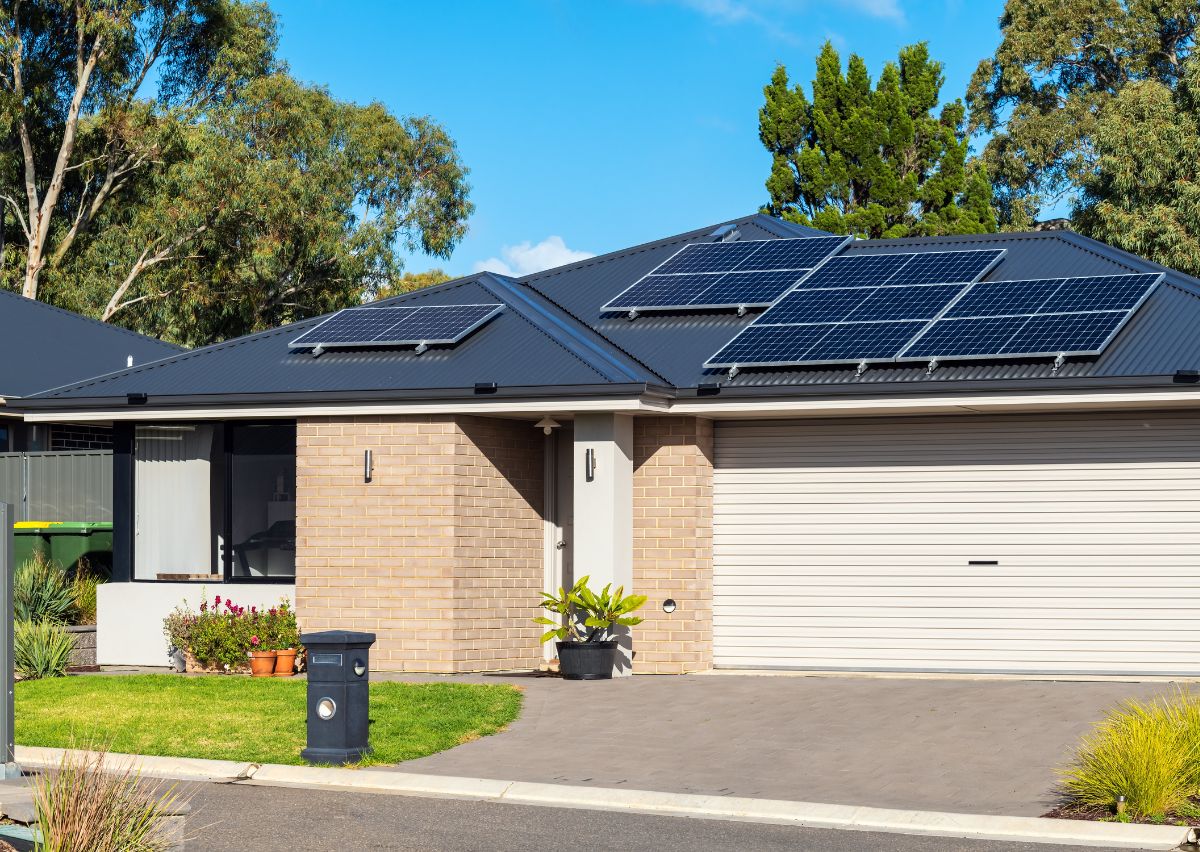 A completed dark metal roof on a brick home with existing solar panels